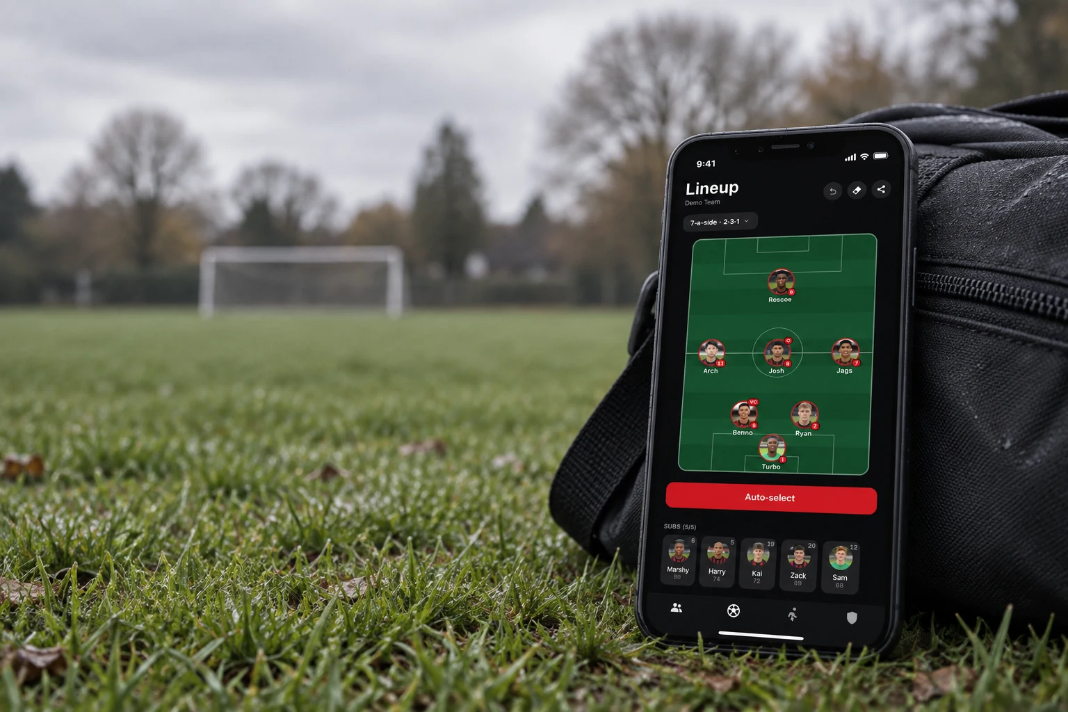 Team Selector lineup screen on a phone resting against a kit bag on a grass pitch